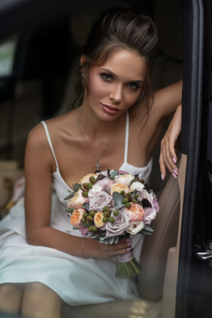 Портрет невесты с букетом в машине